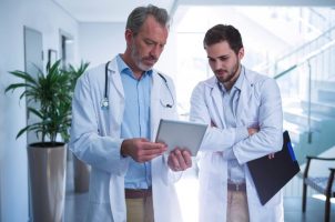 doutores conversando em corredor com tablet na mão | Diferença entre urologista e proctologista